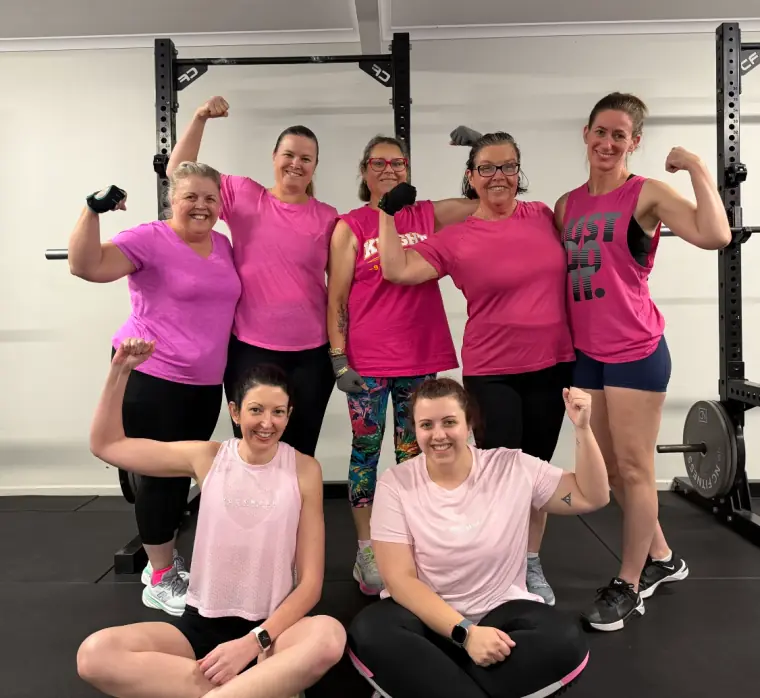 Women's Club members in pink flexing together at a themed session